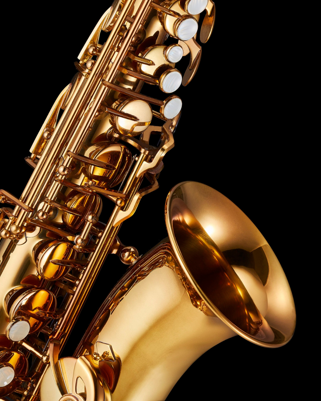 Close-up of a polished golden saxophone against a black background, showing its keys, pads, and flared bell
